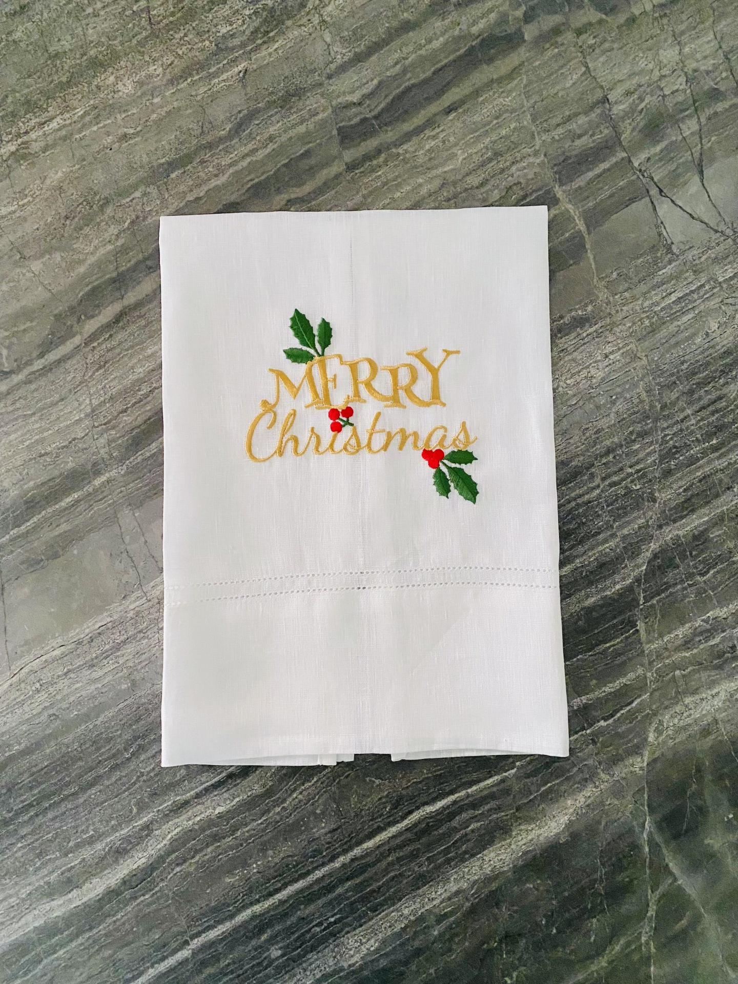 Toalha branca bordada com a frase Merry Christmas em dourado e verde