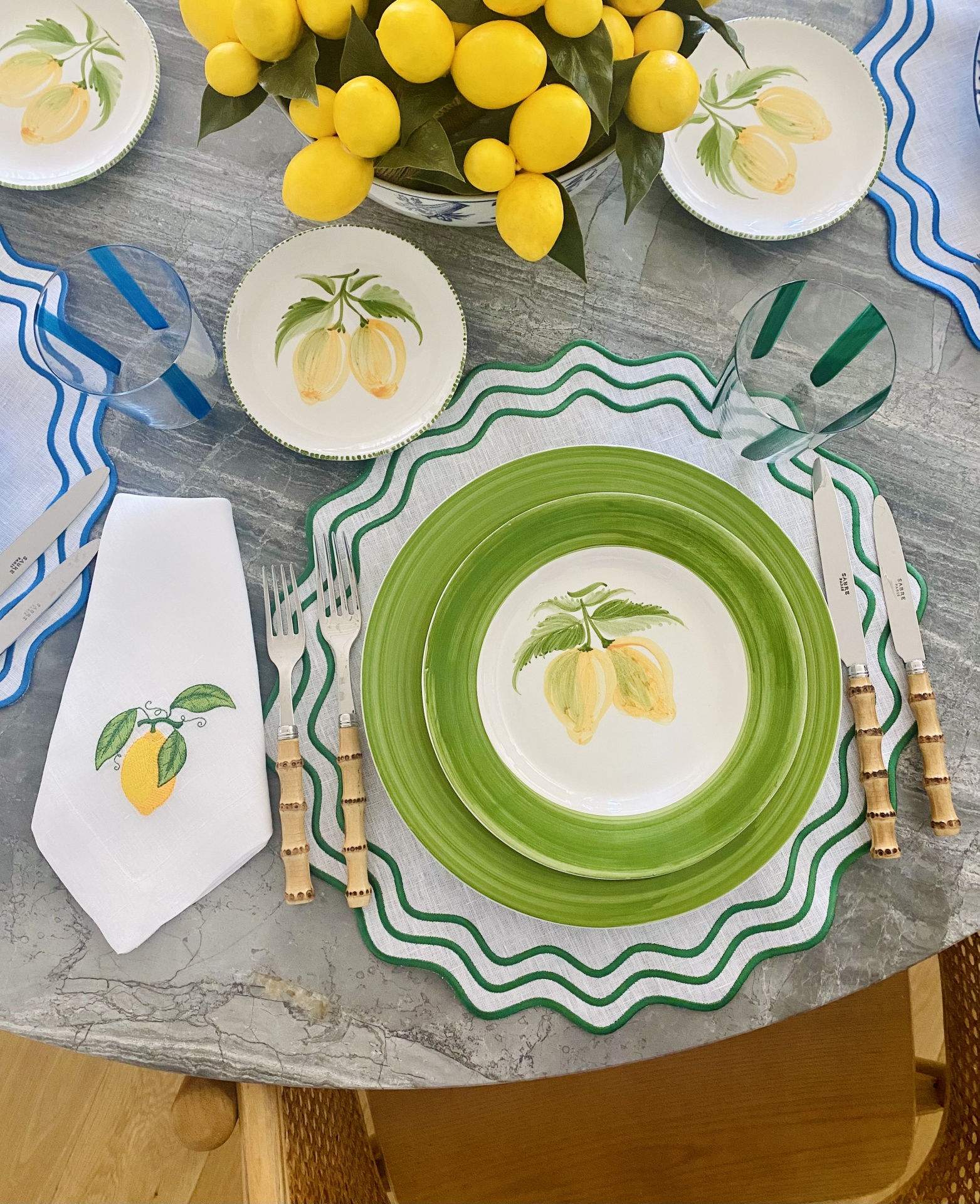 Conjunto de loiça com tema limão e talheres de bambu sobre mesa de mármore