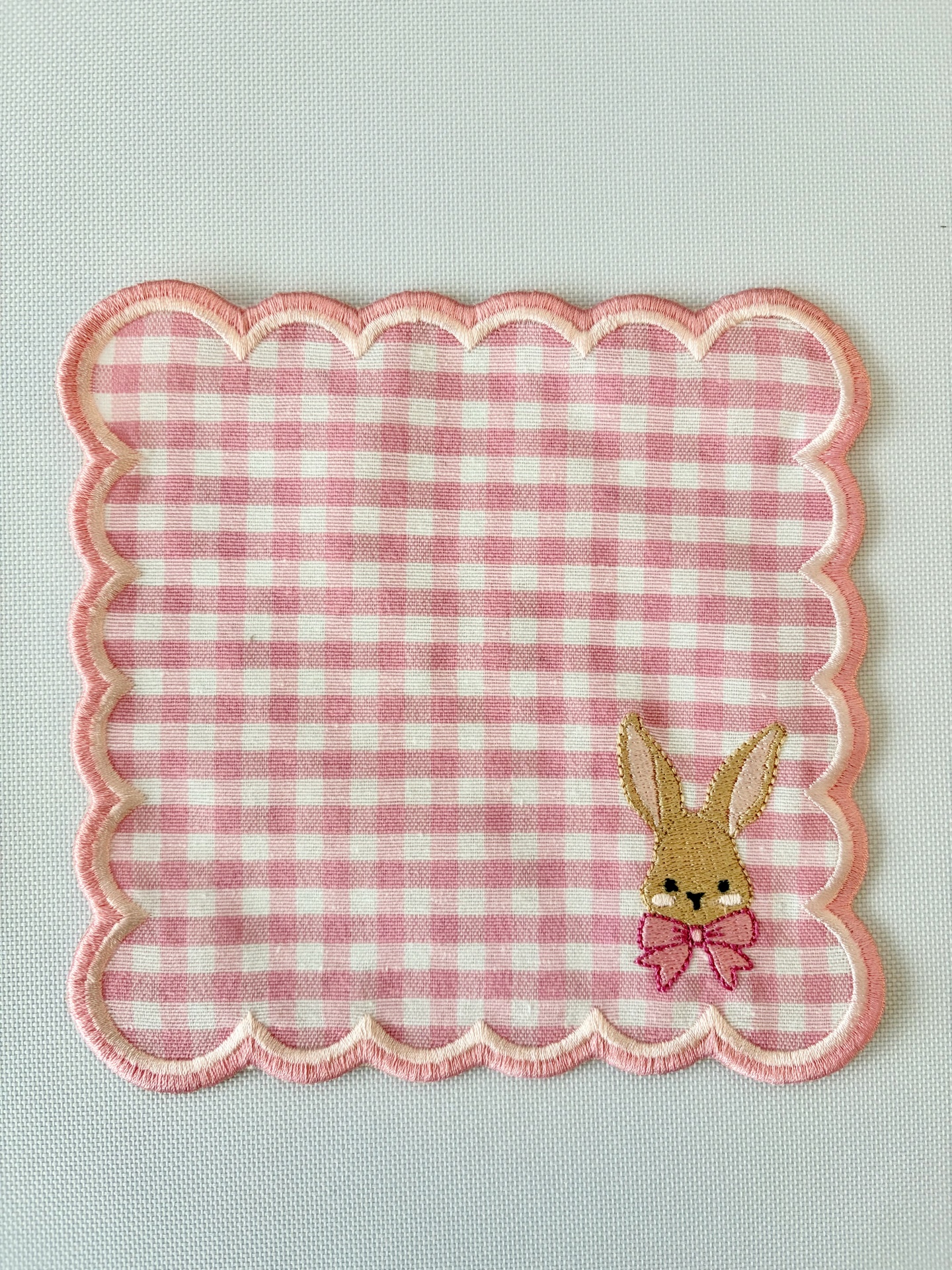 Toalhinha quadrada com padrão rosa e branco e coelho bordado