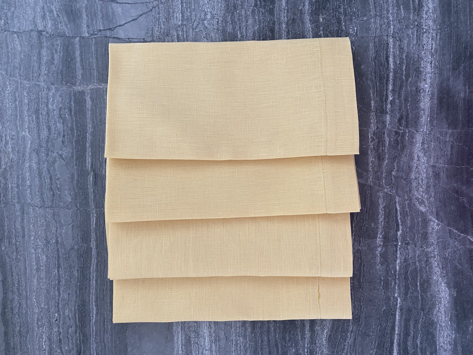 Panos de cozinha amarelos empilhados sobre superfície cinza texturada