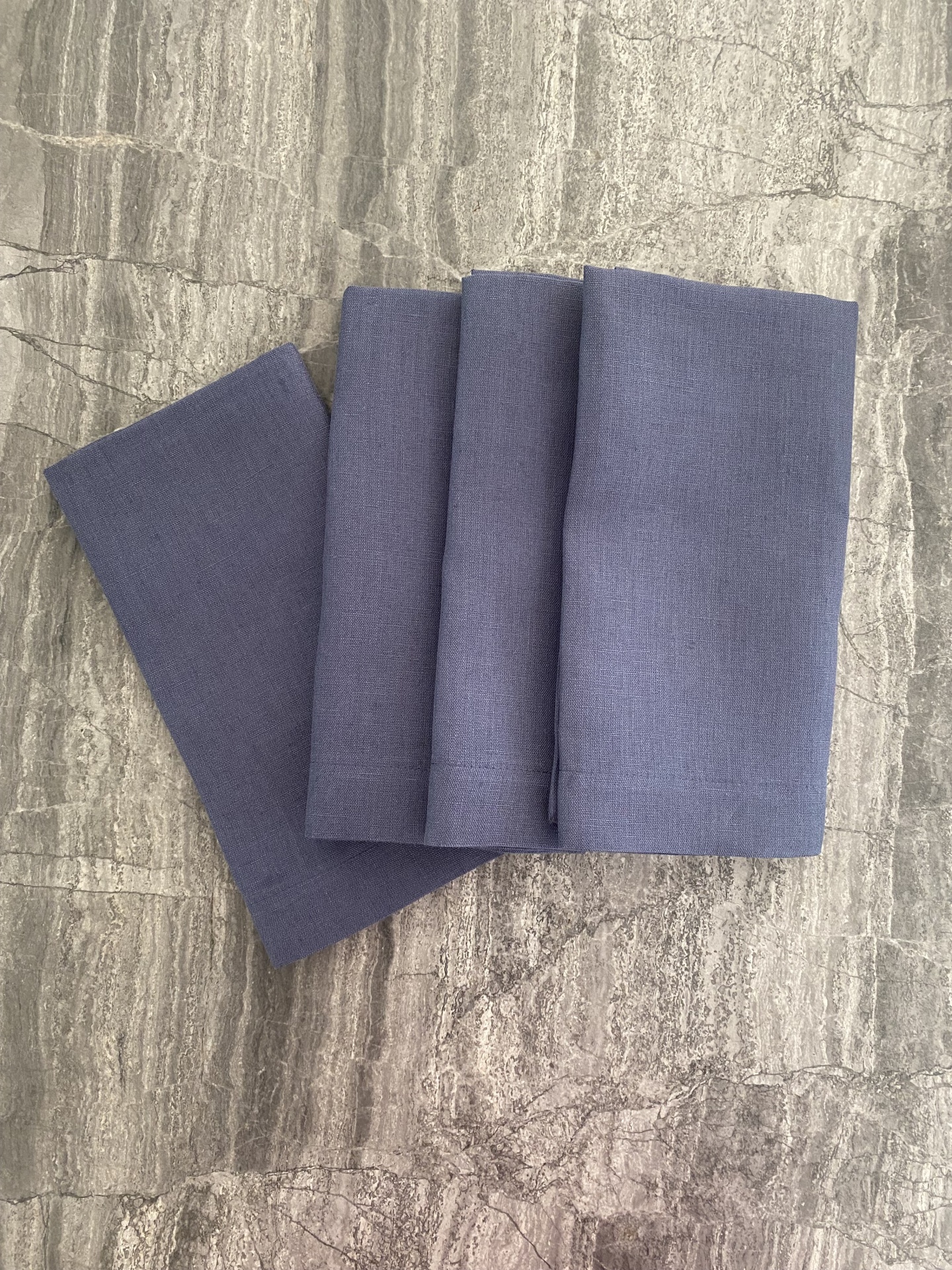 Quatro toalhas cinzentas azuis arrumadas sobre piso de pedra cinzenta
