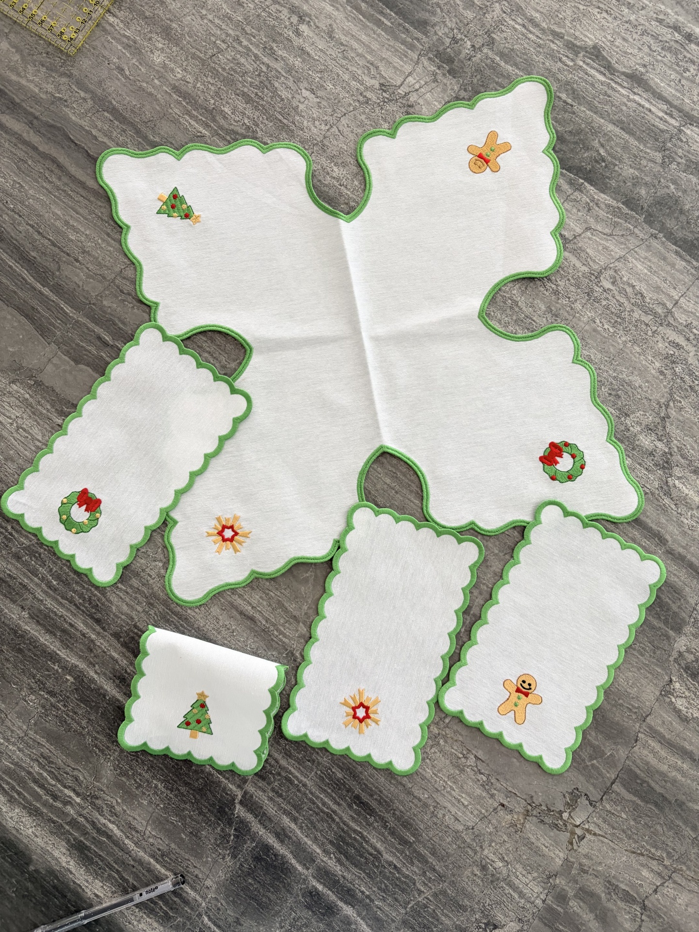 Conjunto de peças de tecido com bordas verdes e motivos natalinos bordados.