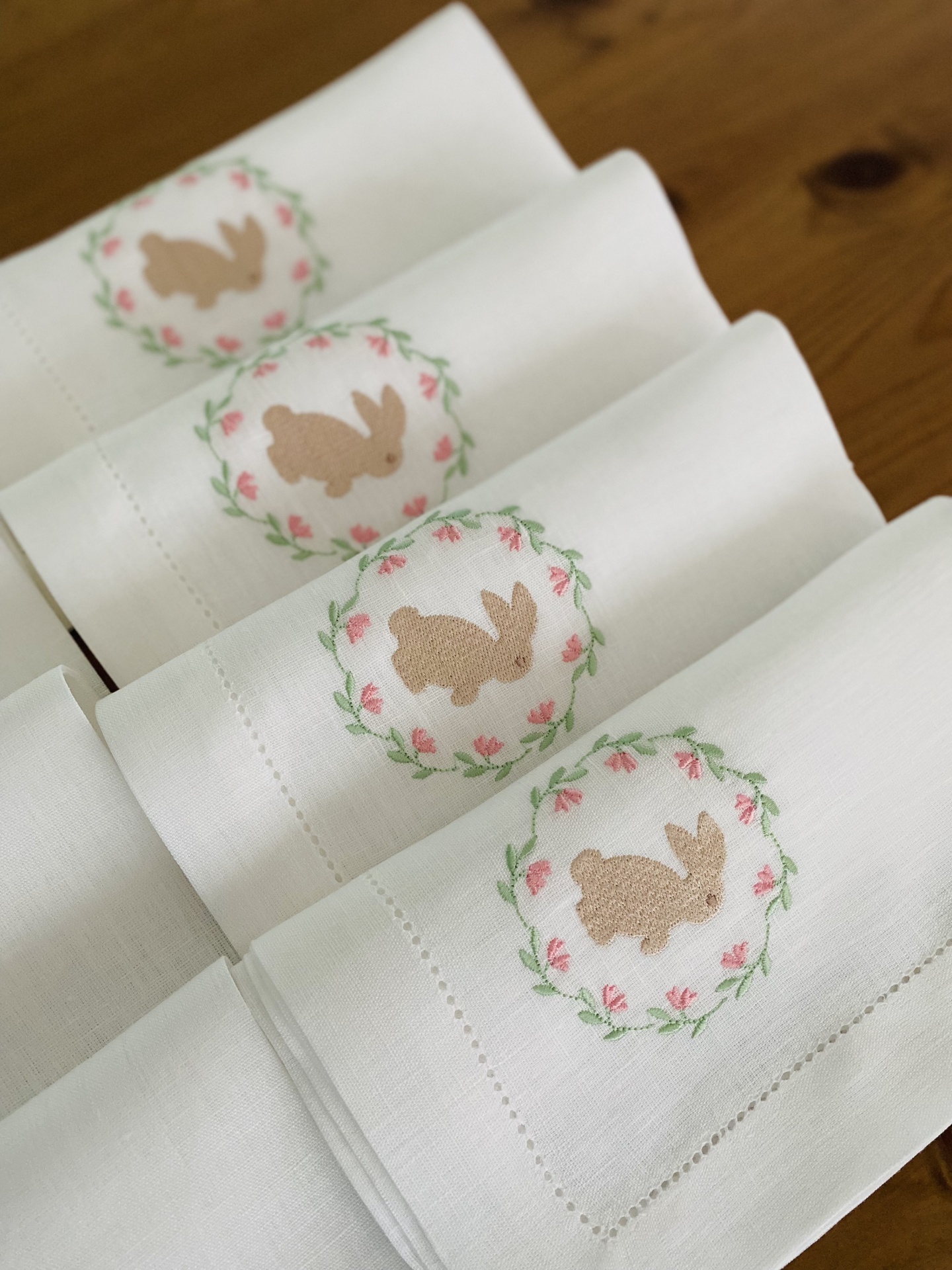 Quatro toalhas brancas com bordado de coelhos em coroa floral rosa e verde