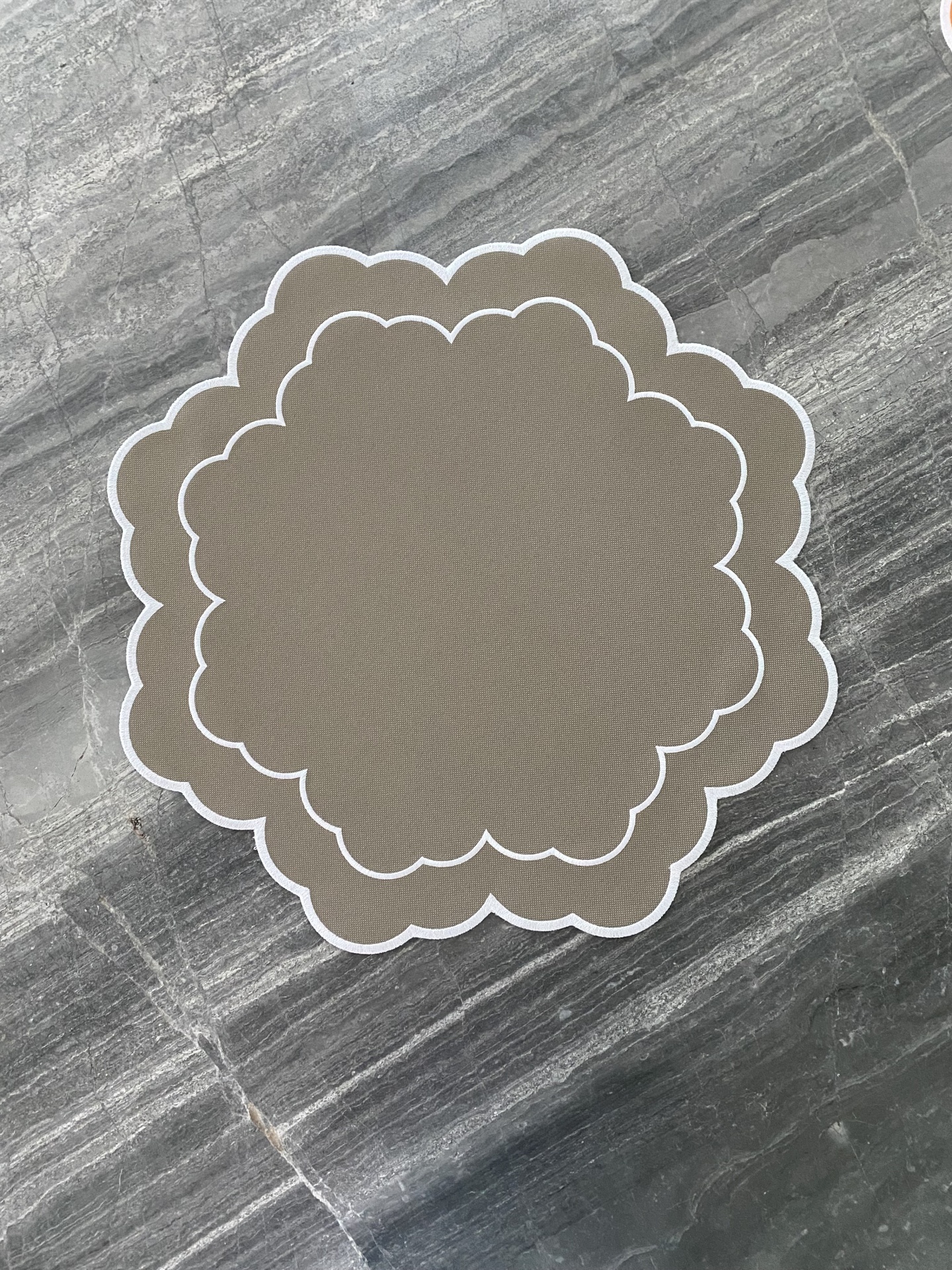 Tapetes bege com borda branca sobre superfície de pedra cinzenta