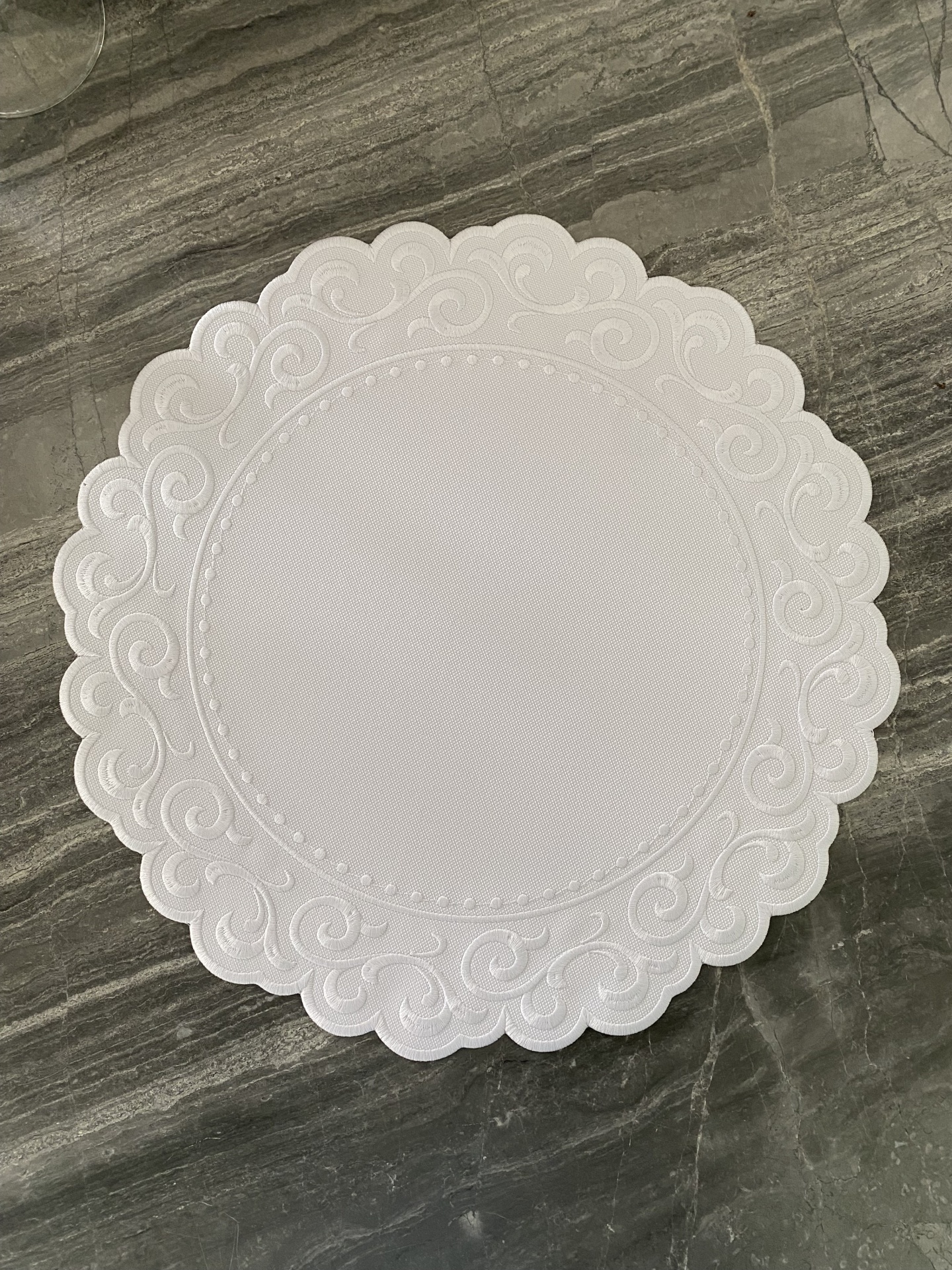 Guardanapo branco redondo com padrão em relevo nas bordas