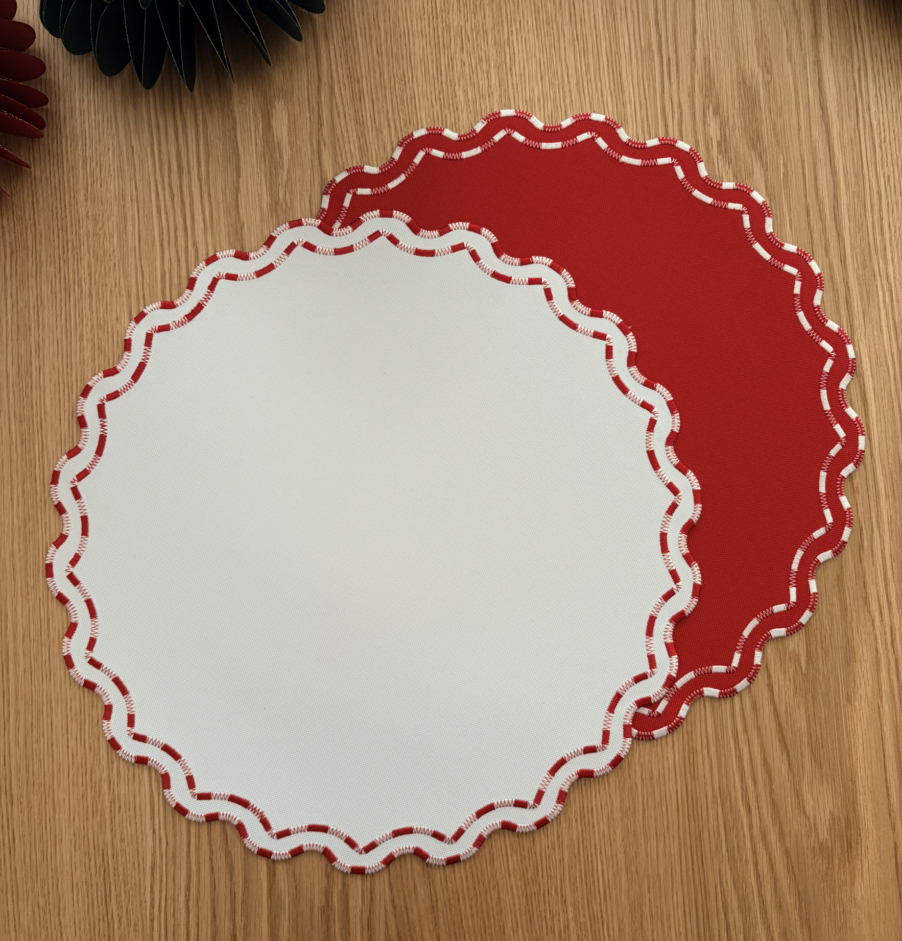Jogos americanos em tecido vermelho e branco com bordas onduladas sobre madeira.
