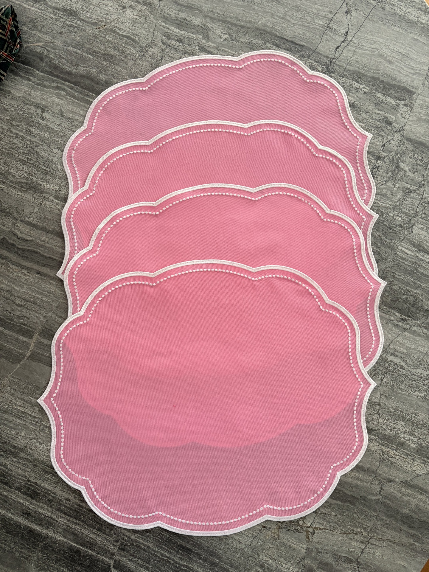 Conjunto de bases de mesa rosa com bordas brancas sobre chão cinzento
