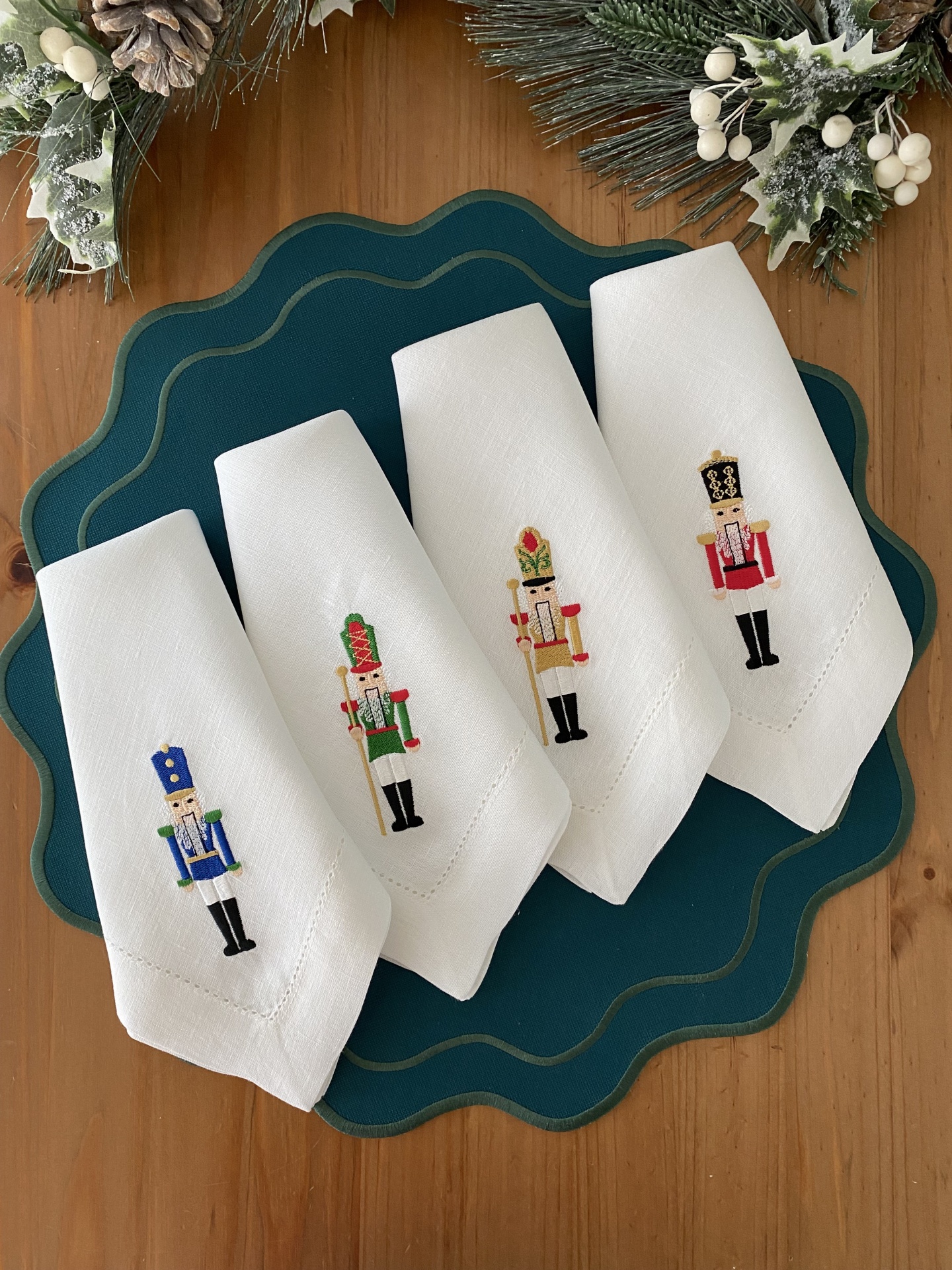 Guardanapos brancos com bordados de soldados coloridos sobre bases azuis com decoração natalícia