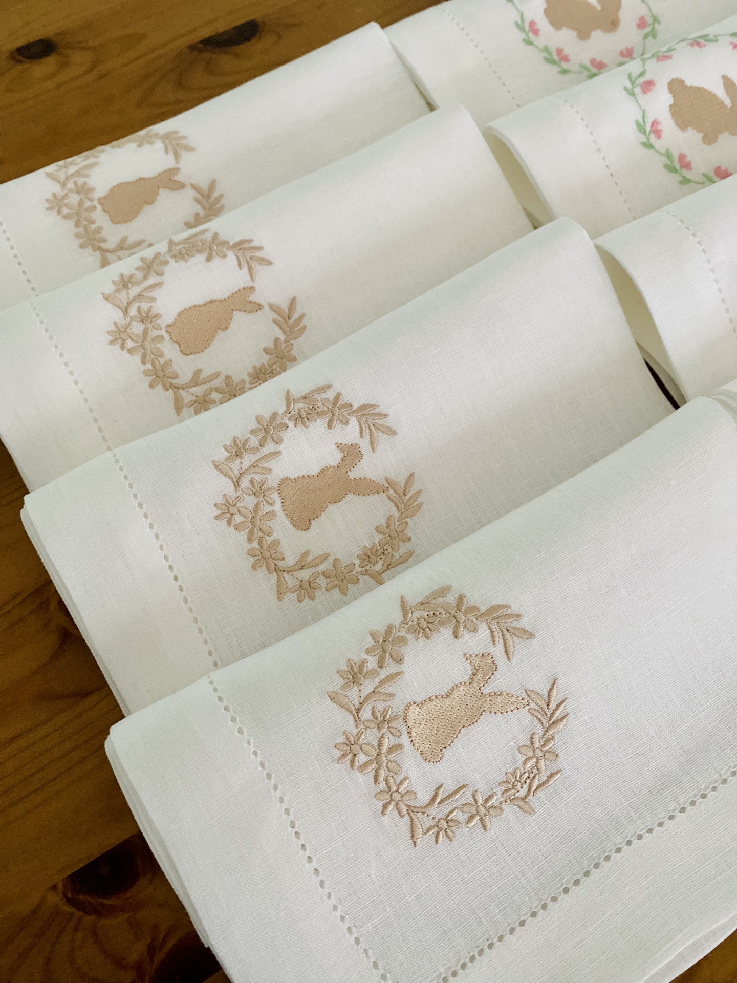 Guardanapos brancos bordados com coelhos bege dobrados sobre madeira