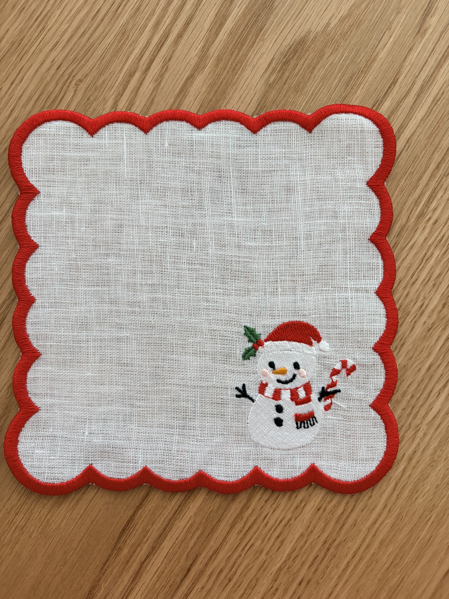 Pano branco com bordas vermelhas e boneco de neve bordado no canto