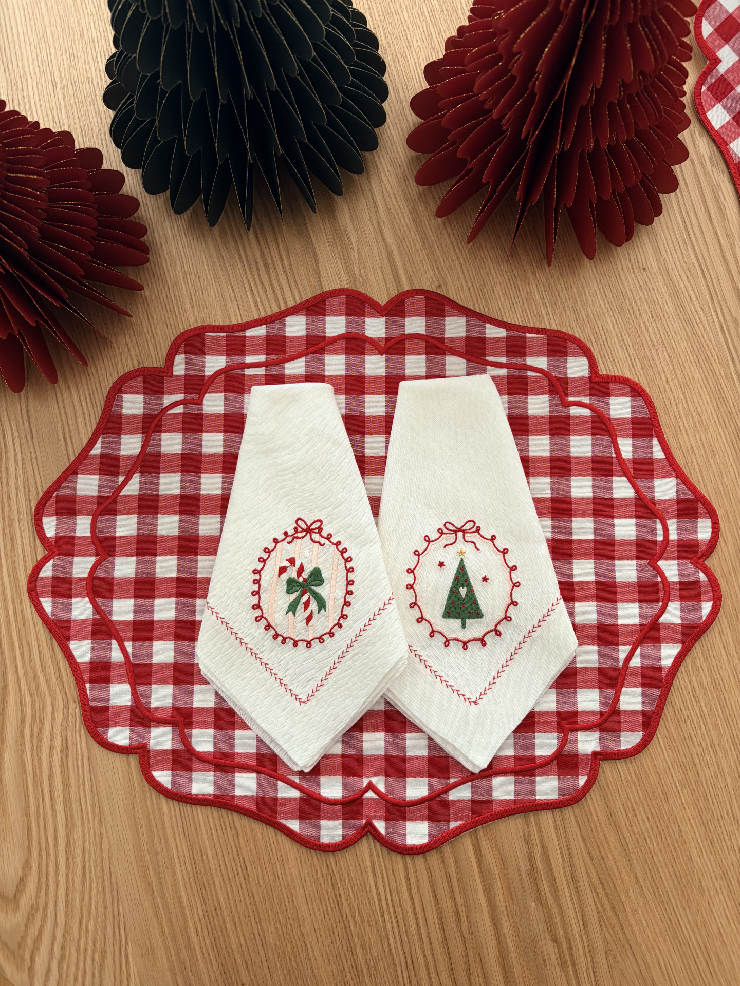 bases de mesa xadrez vermelha e branca com dois guardanapos brancos bordados e decoração em papel
