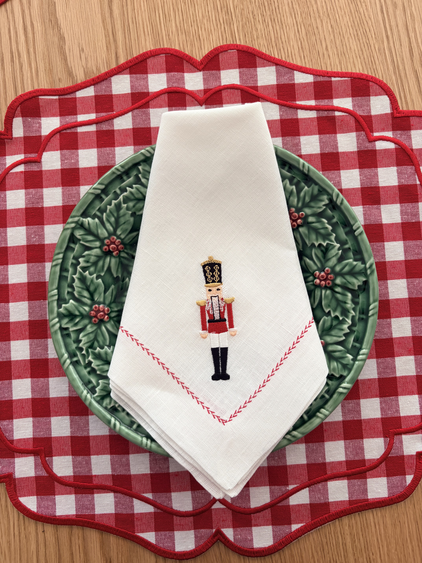 Individuais xadrez vermelho e branco, prato verde decorativo e guardanapo branco com soldadinho bordado
