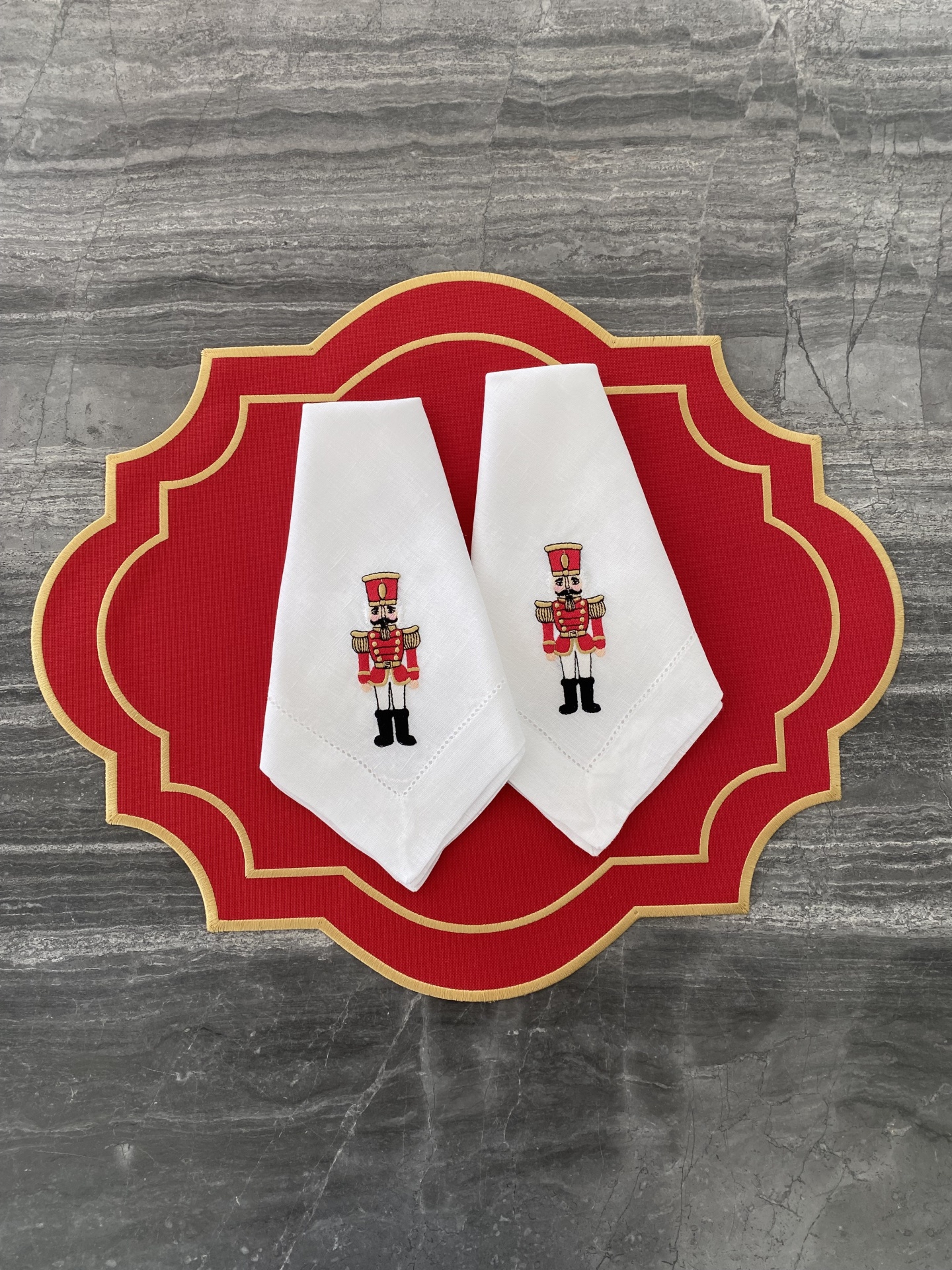Dois guardanapos brancos com soldados bordados em suporte vermelho com dourado