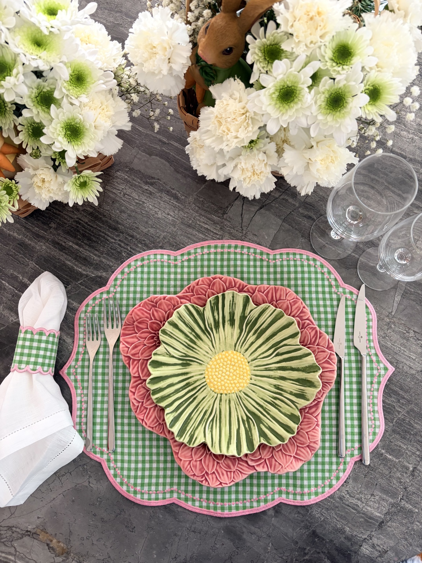 Conjunto de louça decorativa floral sobre base xadrez com talheres e guarda-napo à mesa