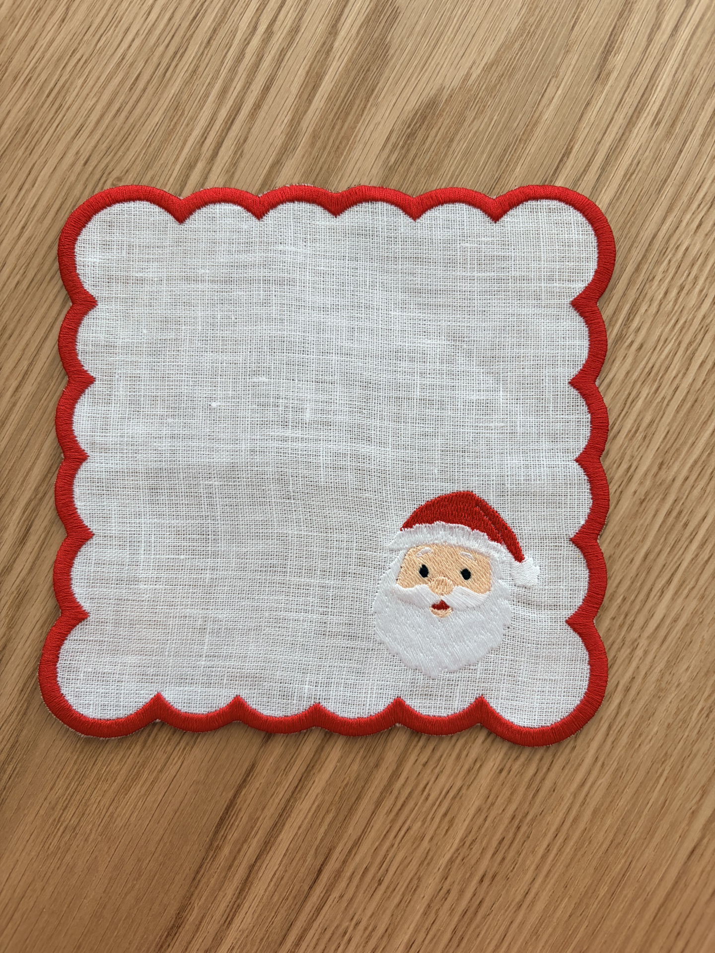 Guardanapo branco com borda vermelha e bordado de Pai Natal