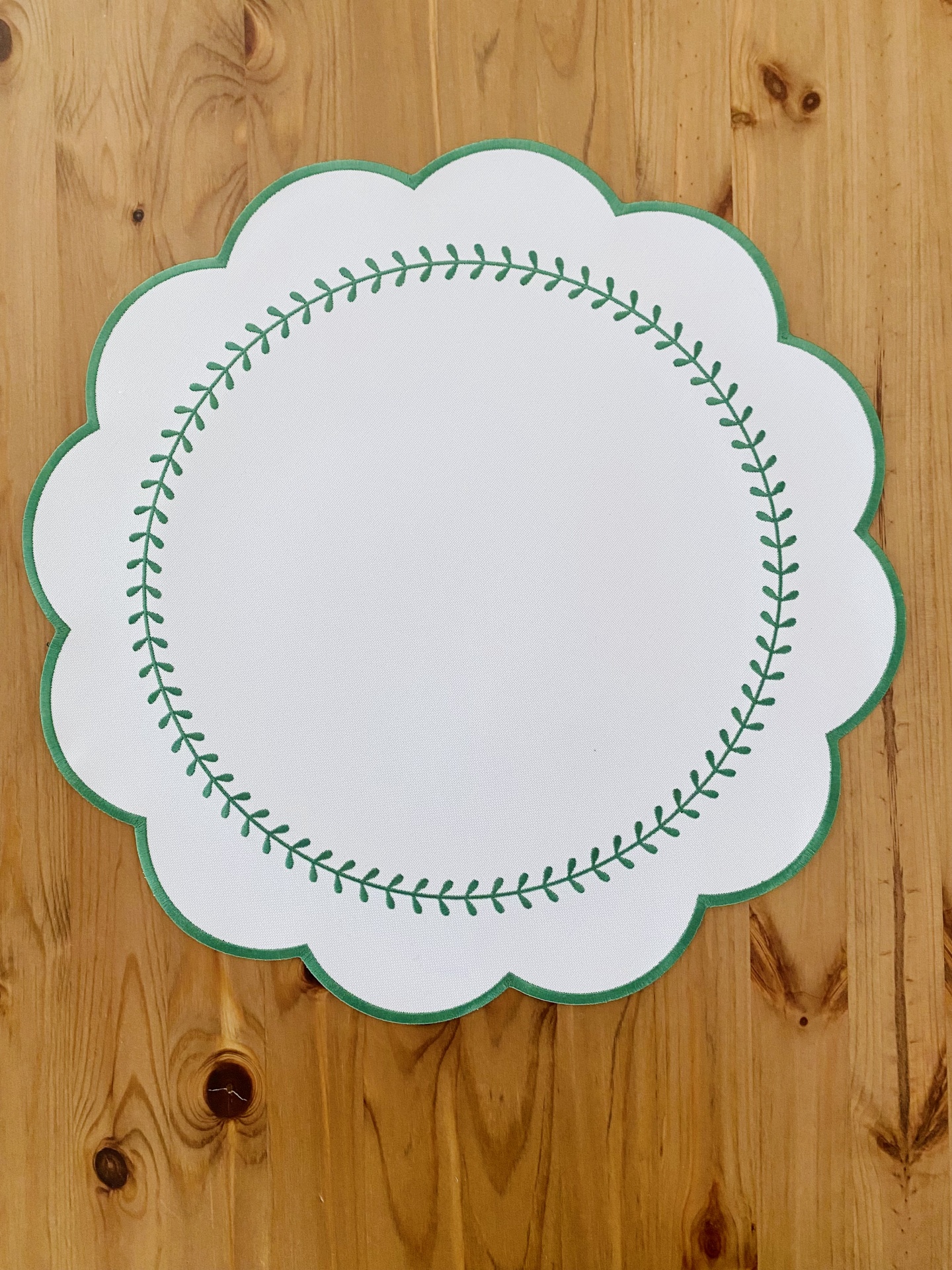 Guardanapo ou toalhete branco com padrão verde sobre mesa de madeira