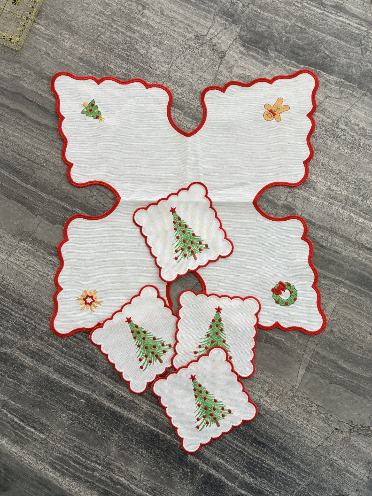 Toalha branca de Natal com bordas vermelhas e motivos bordados sobre superfície de pedra cinzenta