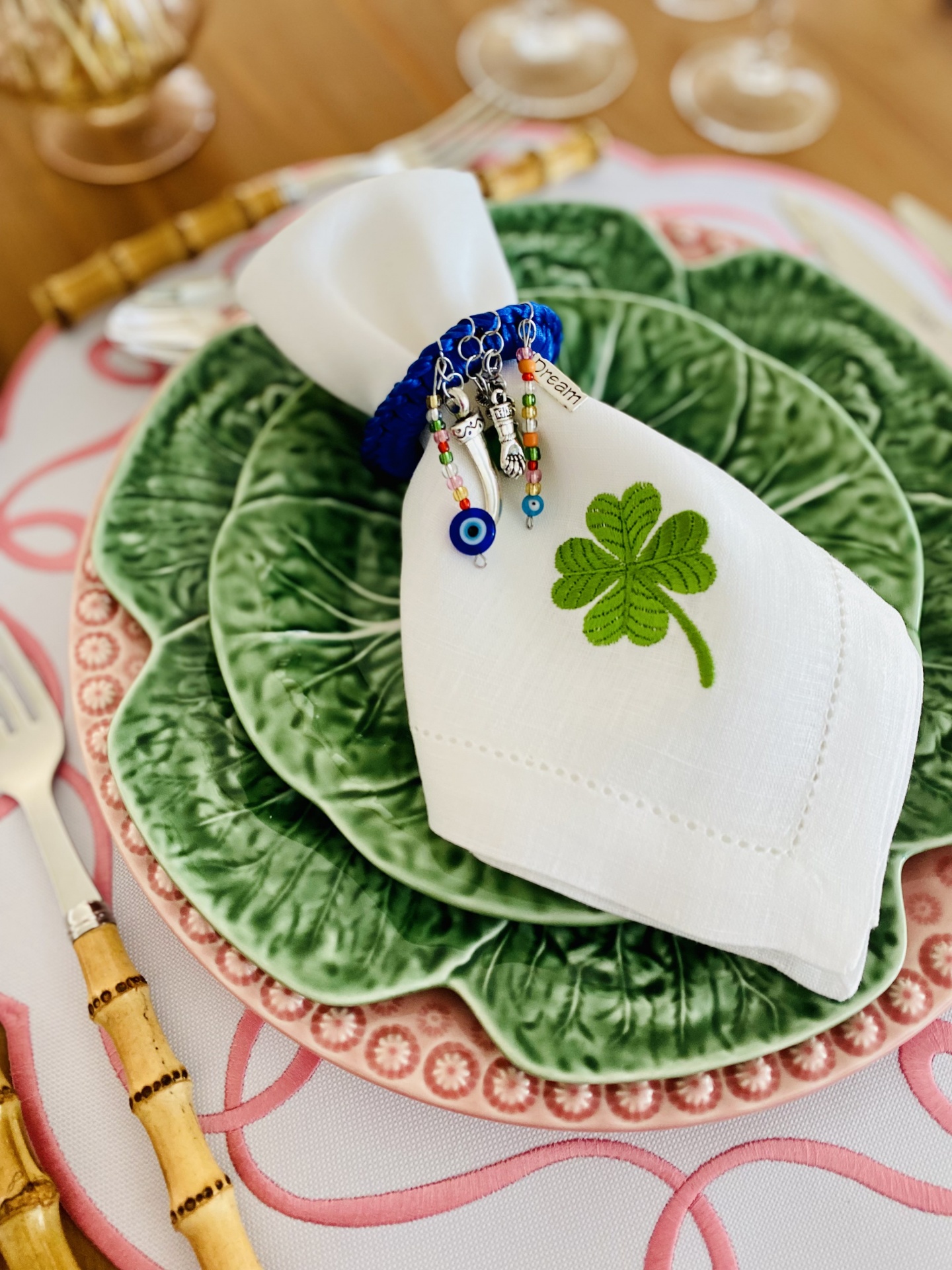 Conjunto de pratos verdes formato folha com guardanapo branco e anel decorativo azul sobre mesa arrumada.