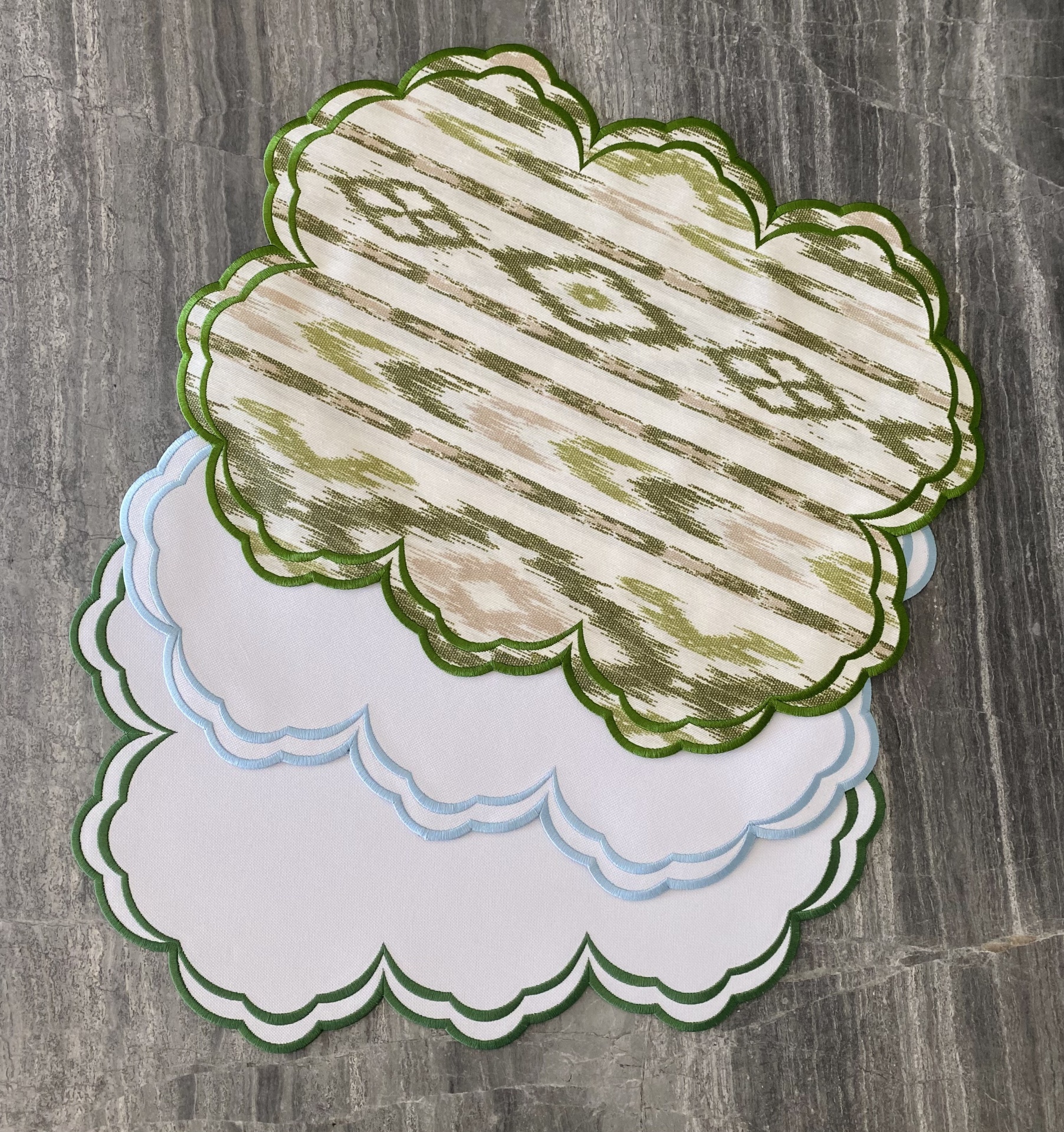 Quatro toalhetes com bordas onduladas e padrão têxtil sobre superfície cinza