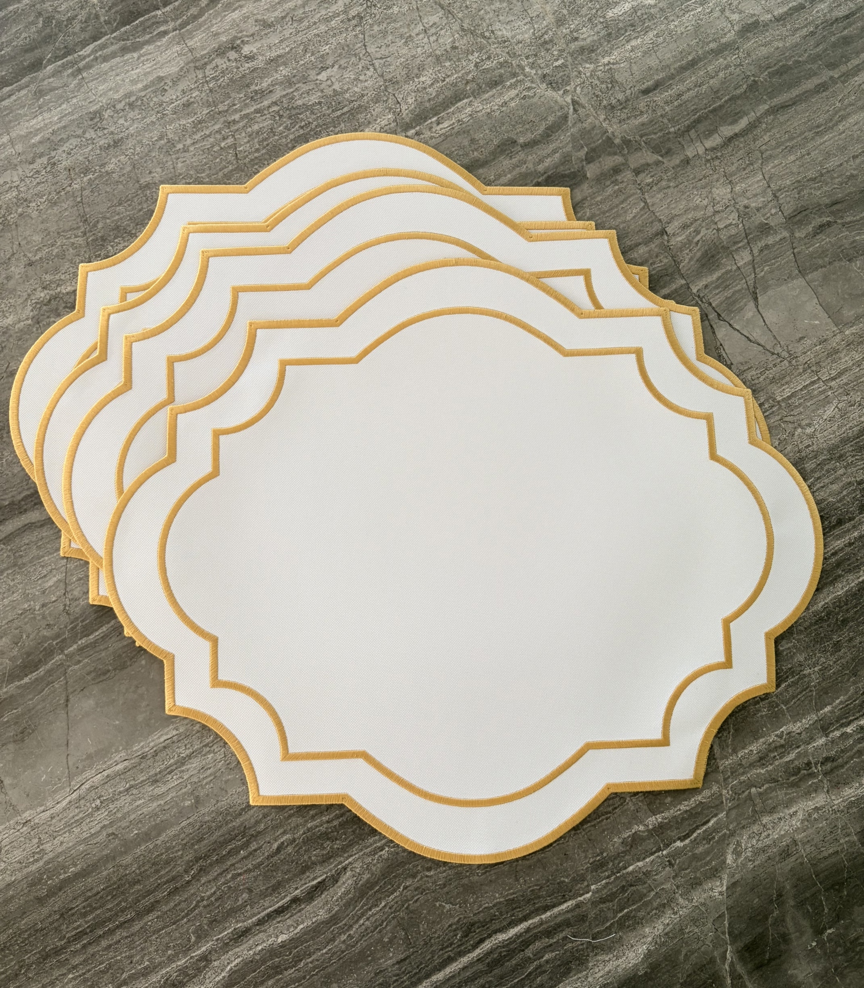 Conjunto de etiquetas em papel branco com bordas douradas sobre superfície de pedra cinza