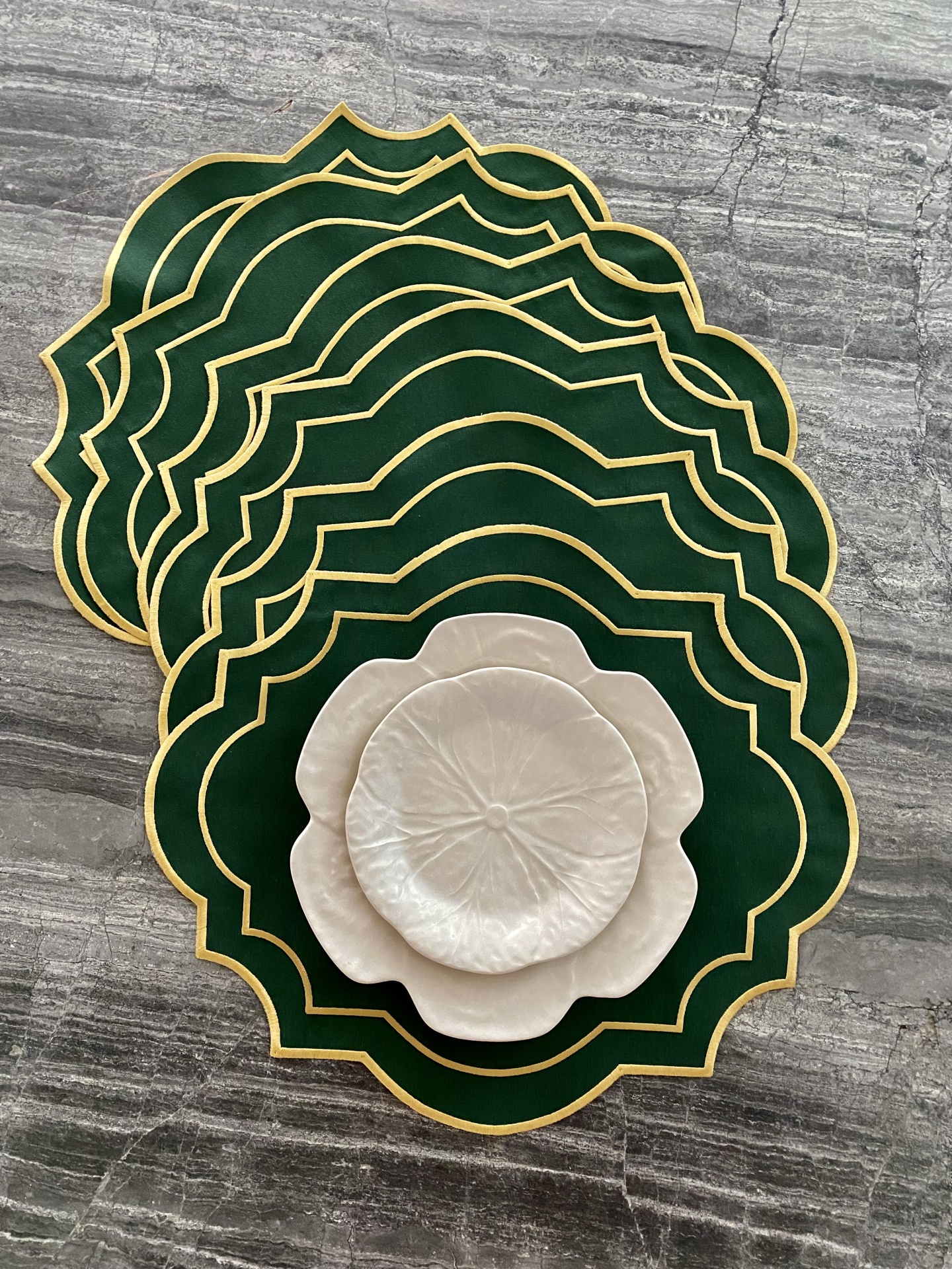 Conjunto de bases de mesa verdes com borda dourada e pratos decorativos creme em forma de flor