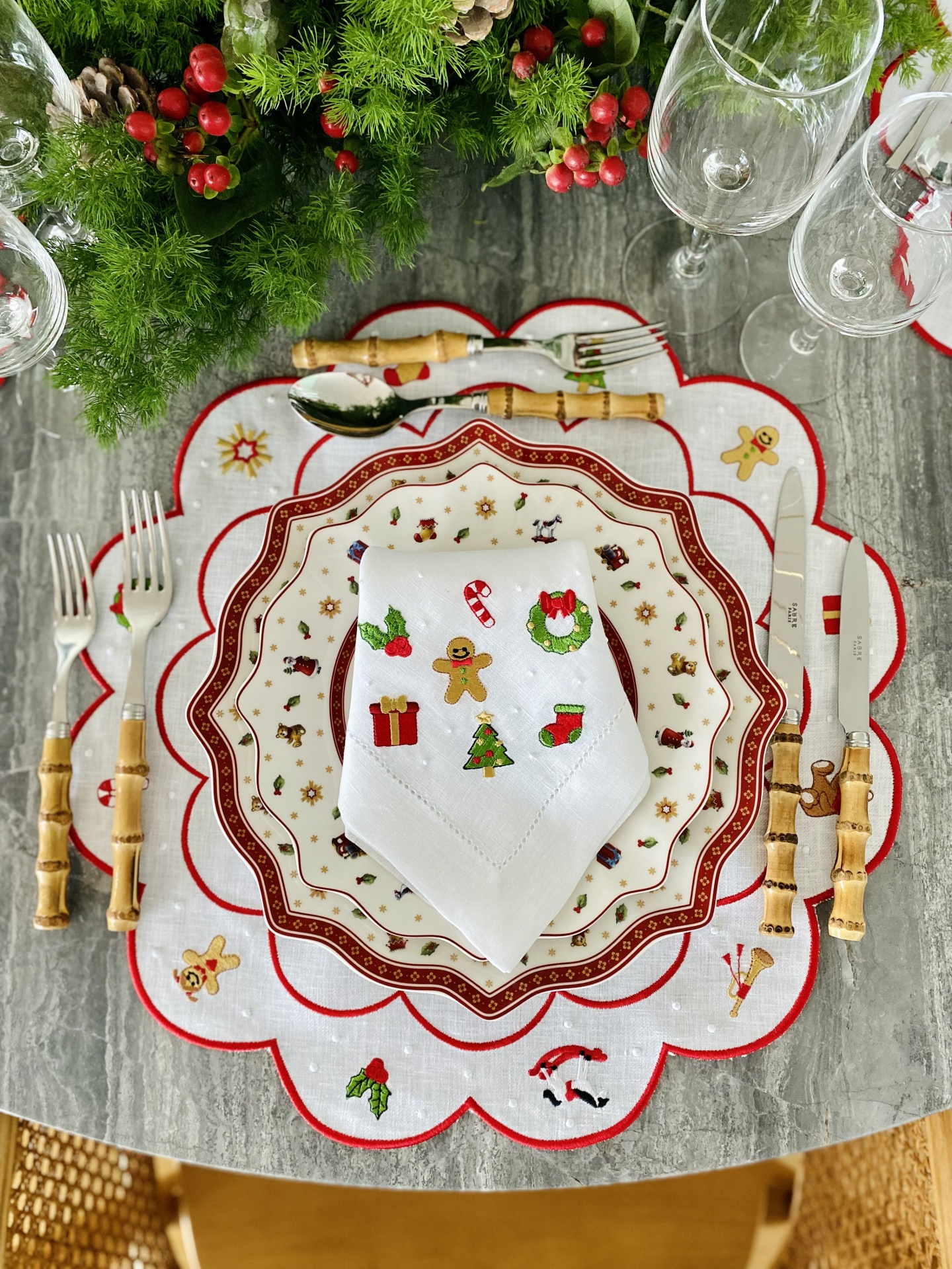 Conjunto de mesa natalício com guardanapo bordado, pratos decorados e talheres com cabos de bambu.