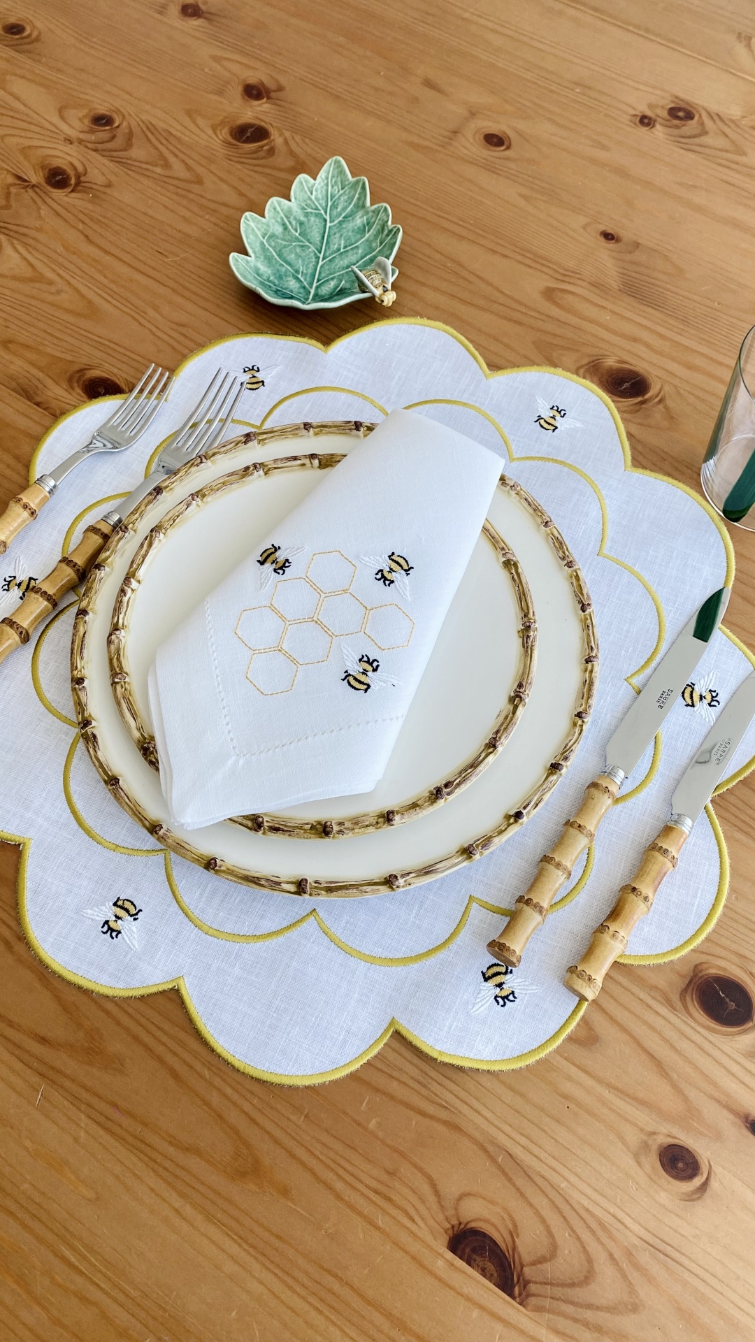 Conjunto de jantar com prato branco decorado, talheres com cabo em bambu, guardanapo e pega prato bordados com abelhas e favo de mel.