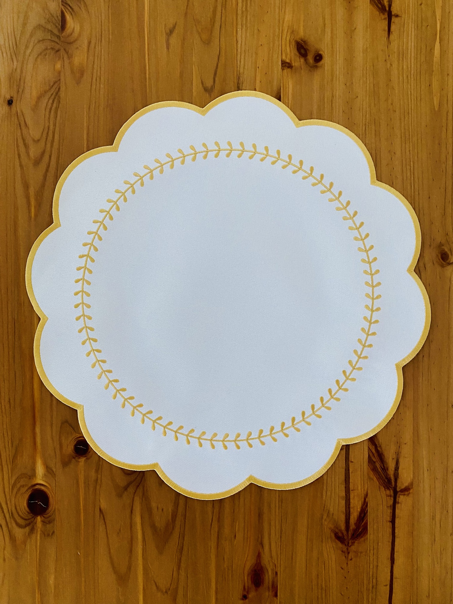 Toalhete branco com padrão dourado sobre madeira clara