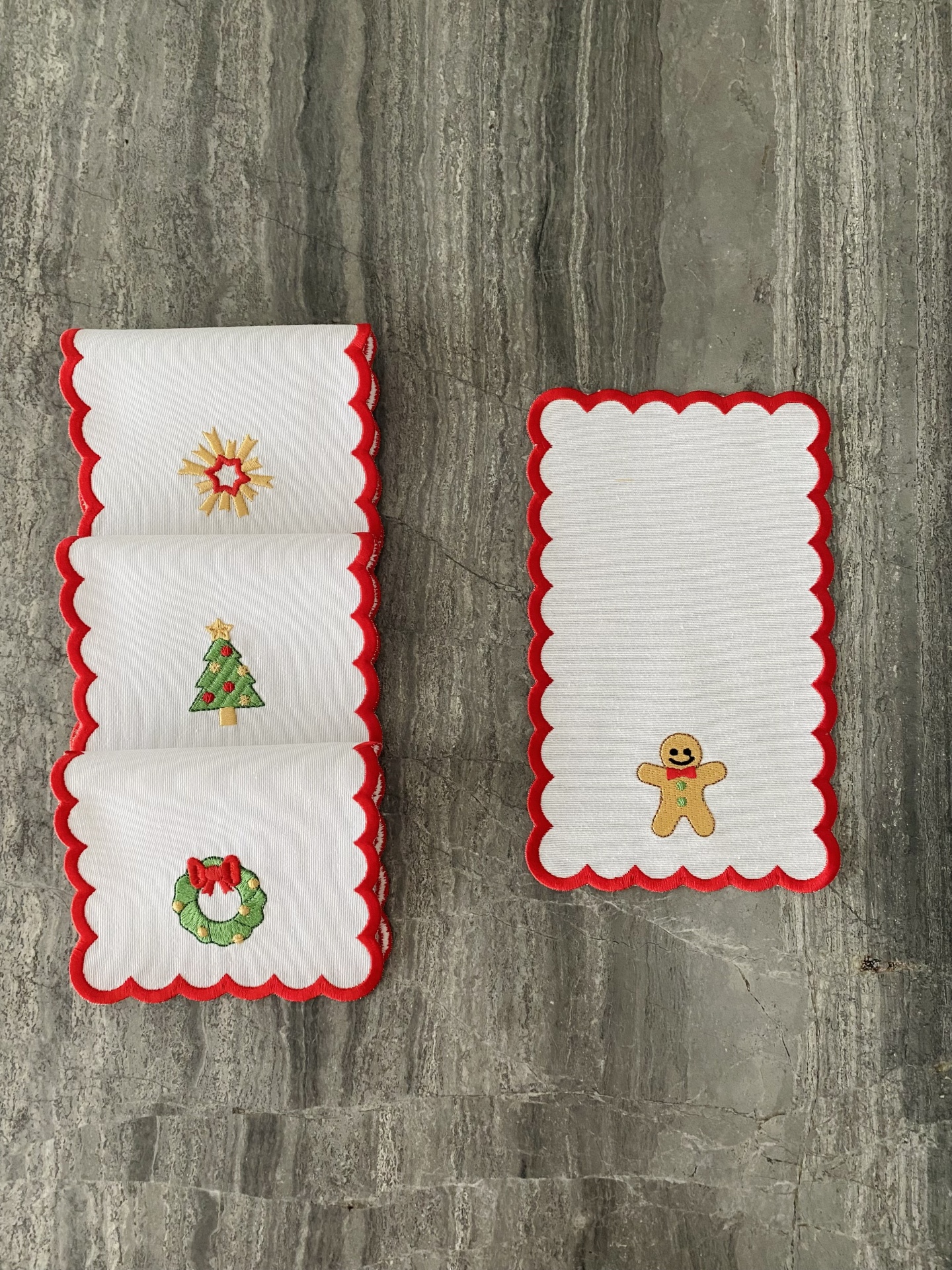 Toalhetes brancos com bordas vermelhas e bordados de Natal, como árvore, estrela, coroa e boneco de gengibre.