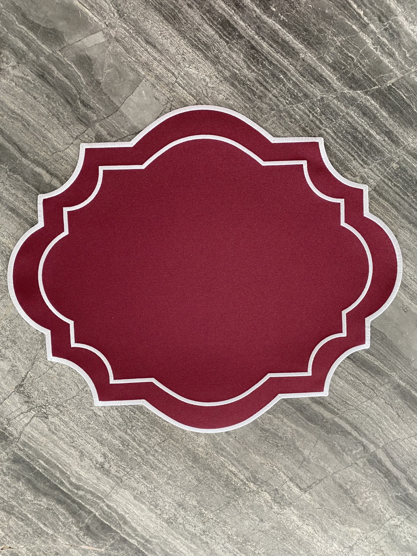 Tapete vermelho com bordas brancas sobre piso cinza marmoreado