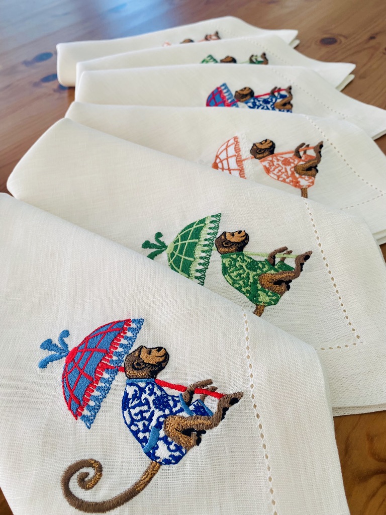 Guardanapos brancos com bordados de macacos coloridos e guarda-chuvas