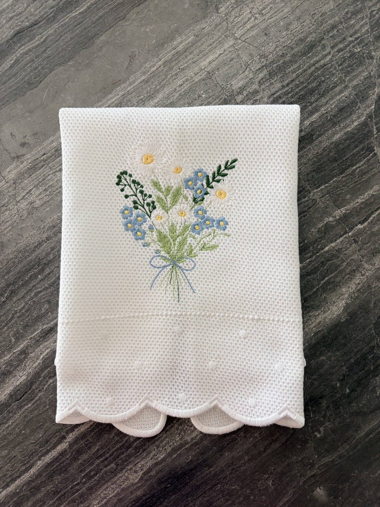 Toalha branca bordada com ramo floral colorido e borda recortada