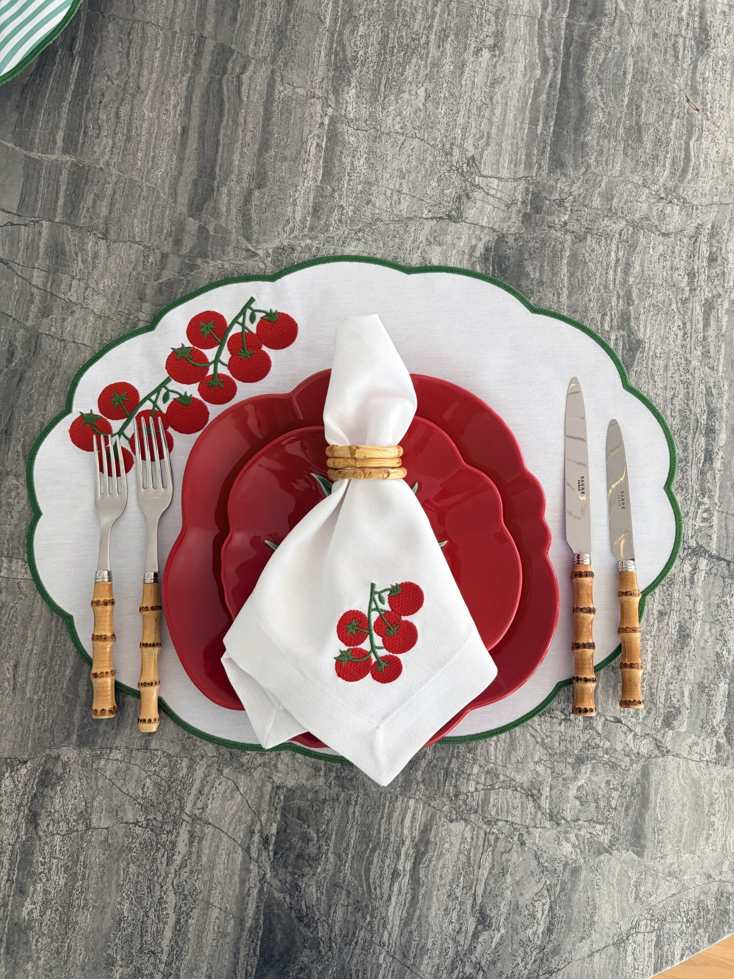 Mesa posta com pratos vermelhos e guardanapo branco com estampa de tomates