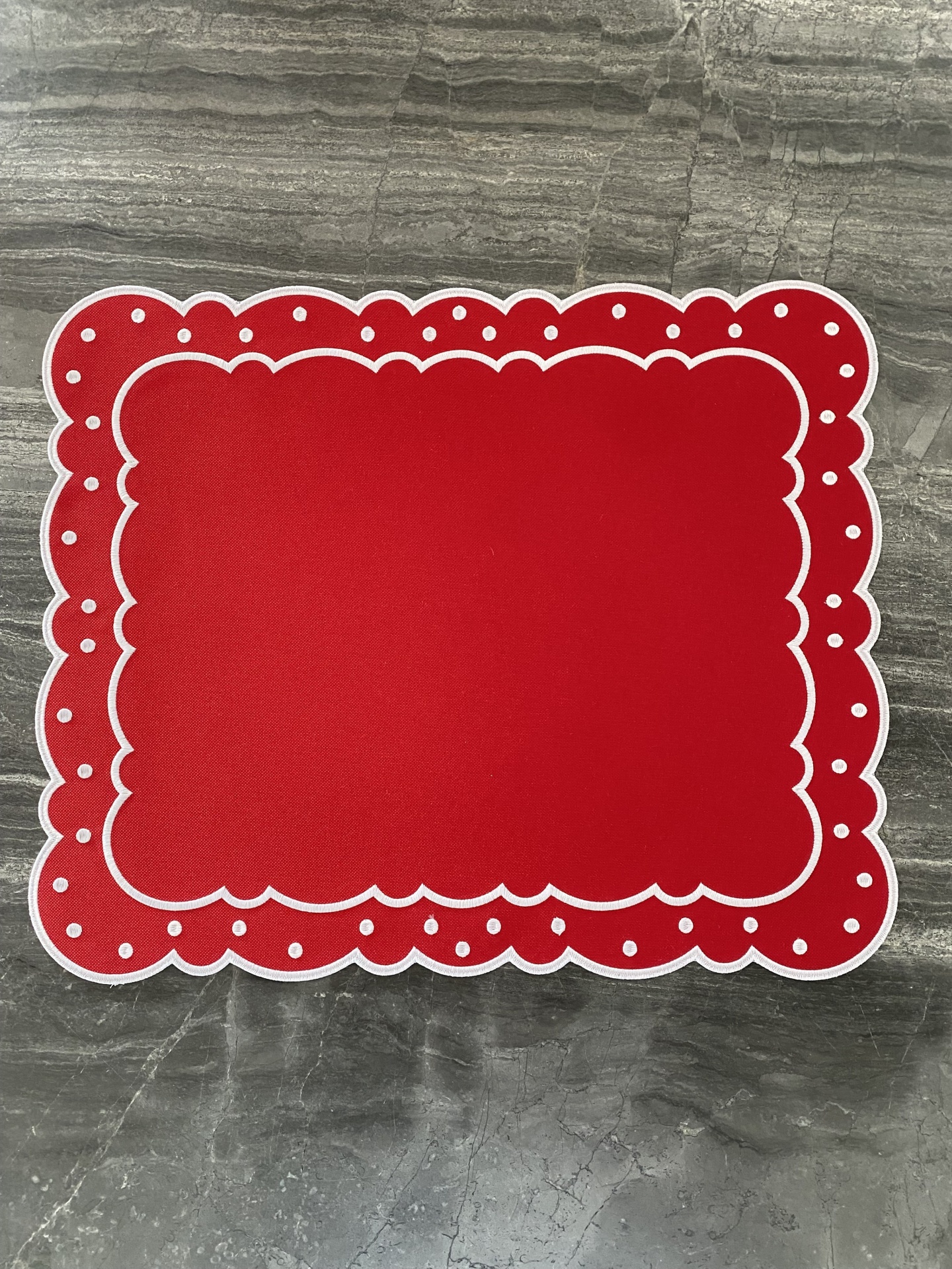 Toalhete vermelho com padrão branco e pontos brancos sobre superfície cinza