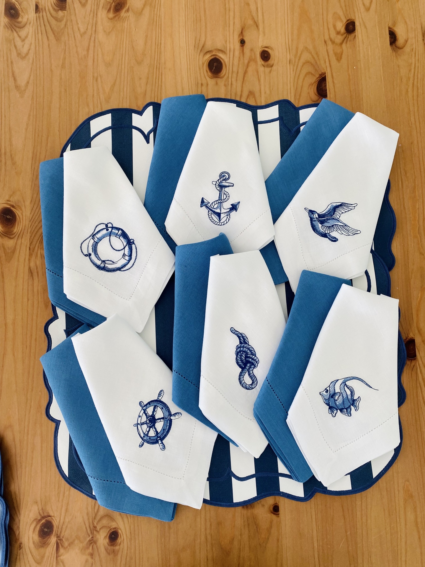 Guardanapos de tecido branco com bordados náuticos azuis sobre base azul e branca