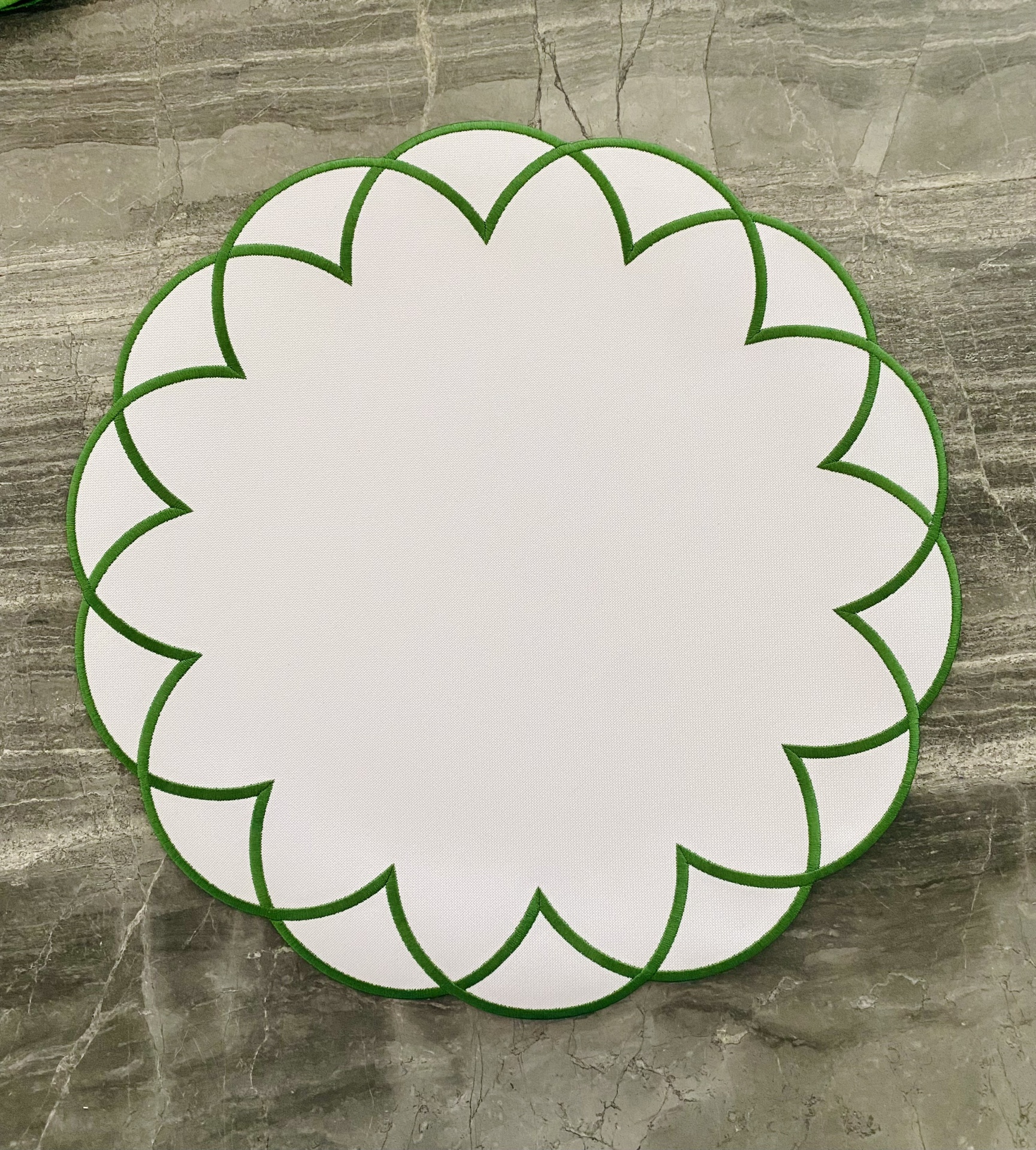 Sousplat redondo branco com borda verde em padrão geométrico em forma de pétalas