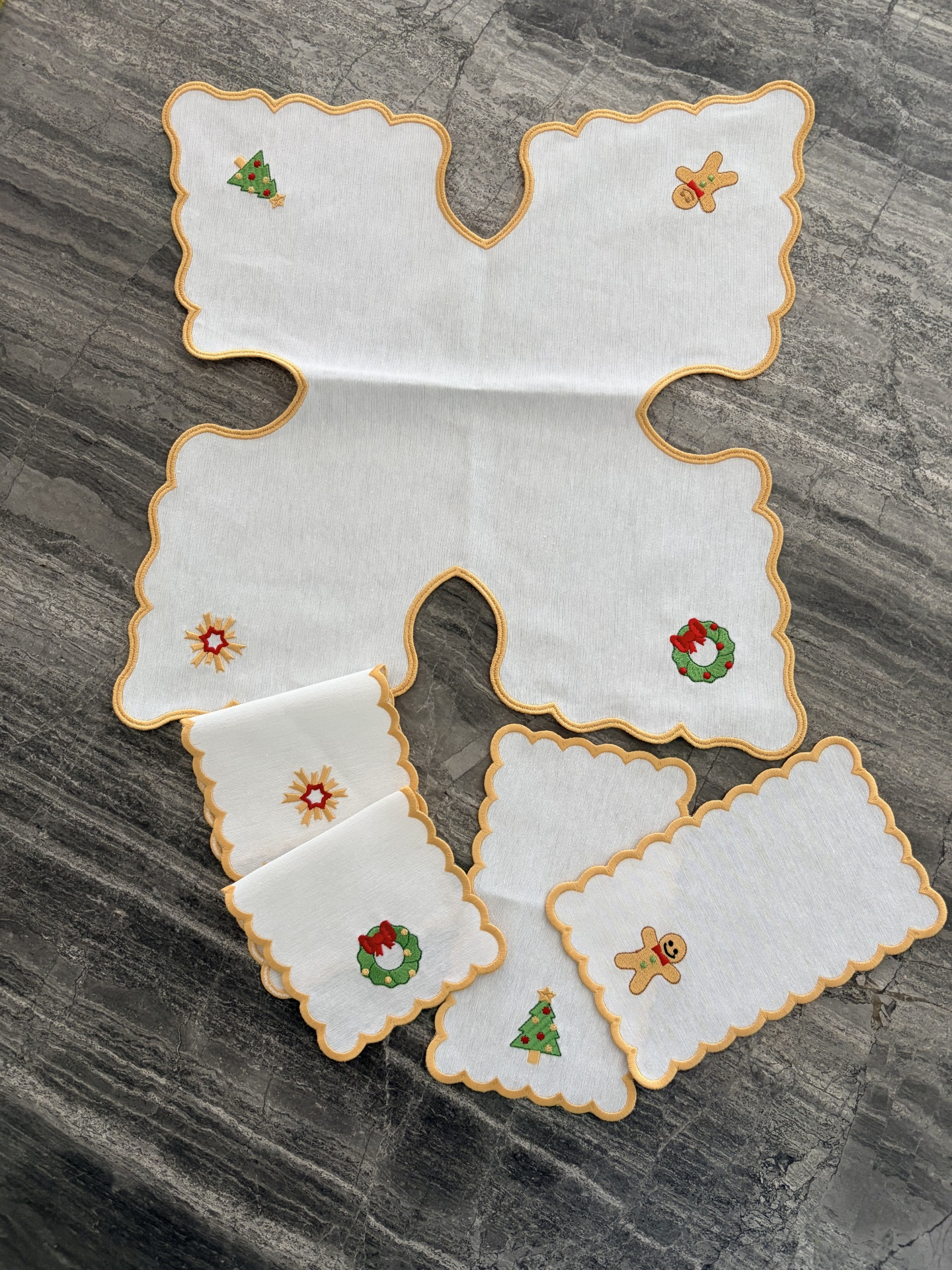 Toalhetes brancos com bordas amarelas e bordados de Natal em superfície cinza