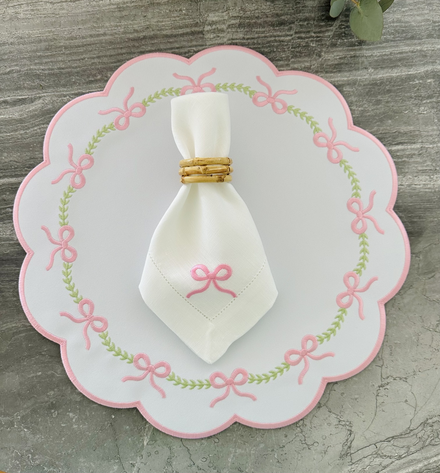 Jogo de mesa com individual branco bordado de laços cor-de-rosa e folhas verdes, toalhete branco com bordado cor-de-rosa e argola de guardanapo natural