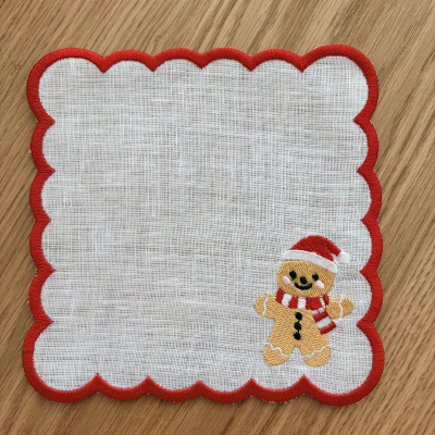 Toalhete branco com borda vermelha e boneco de gengibre bordado.