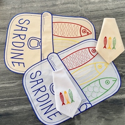 Utensílios de cozinha em tecido com estampas de peixes coloridos sobre superfície cinzenta