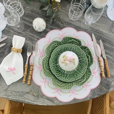 Mesa posta com pratos decorativos verdes e brancos, ovo decorativo, talheres com cabos de bambu e guardanapo branco