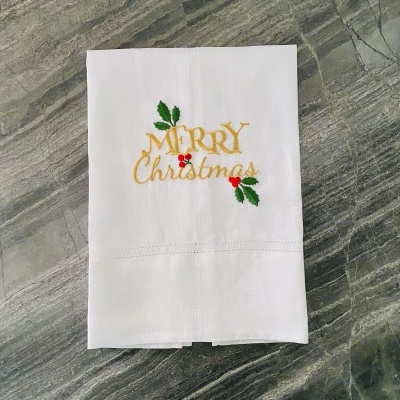 Toalha branca bordada com a frase Merry Christmas em dourado e verde