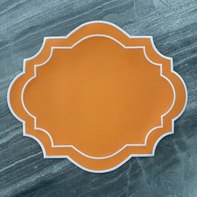 Descanso de mesa laranja com bordas brancas sobre superfície cinza tipo mármore.