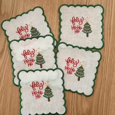 Toalhetes de tecido branco com design de Natal e borda verde sobre madeira