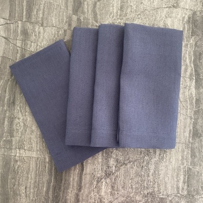 Quatro toalhas cinzentas azuis arrumadas sobre piso de pedra cinzenta