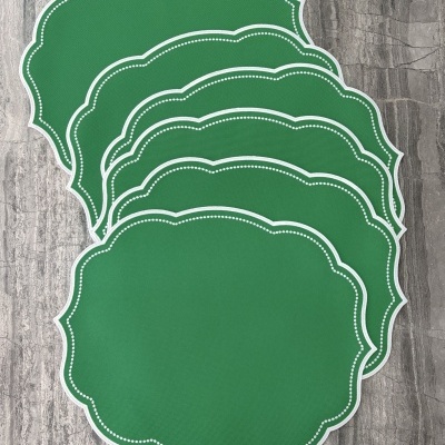 Individuais de mesa verdes com bordas brancas em tecido sobre pedra cinza