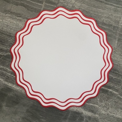 Mesa redonda branca com borda ondulada vermelha sobre chão cinzento