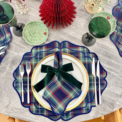 Conjunto de jantar com pratos de porcelana e guardanapos xadrez, copos verdes, talheres de aço, pratos pequenos verdes com relevo, decorados para mesa festiva.