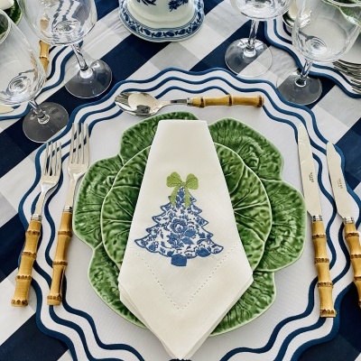 Conjunto de talheres, pratos e guardanapo decorativo sobre mesa listrada azul e branca