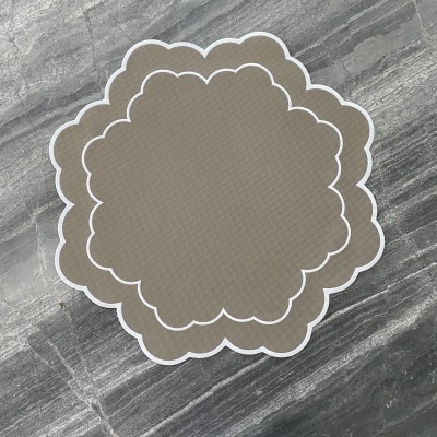 Tapetes bege com borda branca sobre superfície de pedra cinzenta